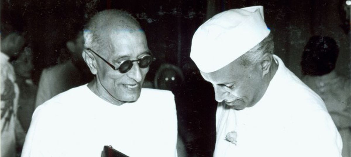 Rajaji in conversation with a fellow Congress leader at a public gathering, both in khadi.